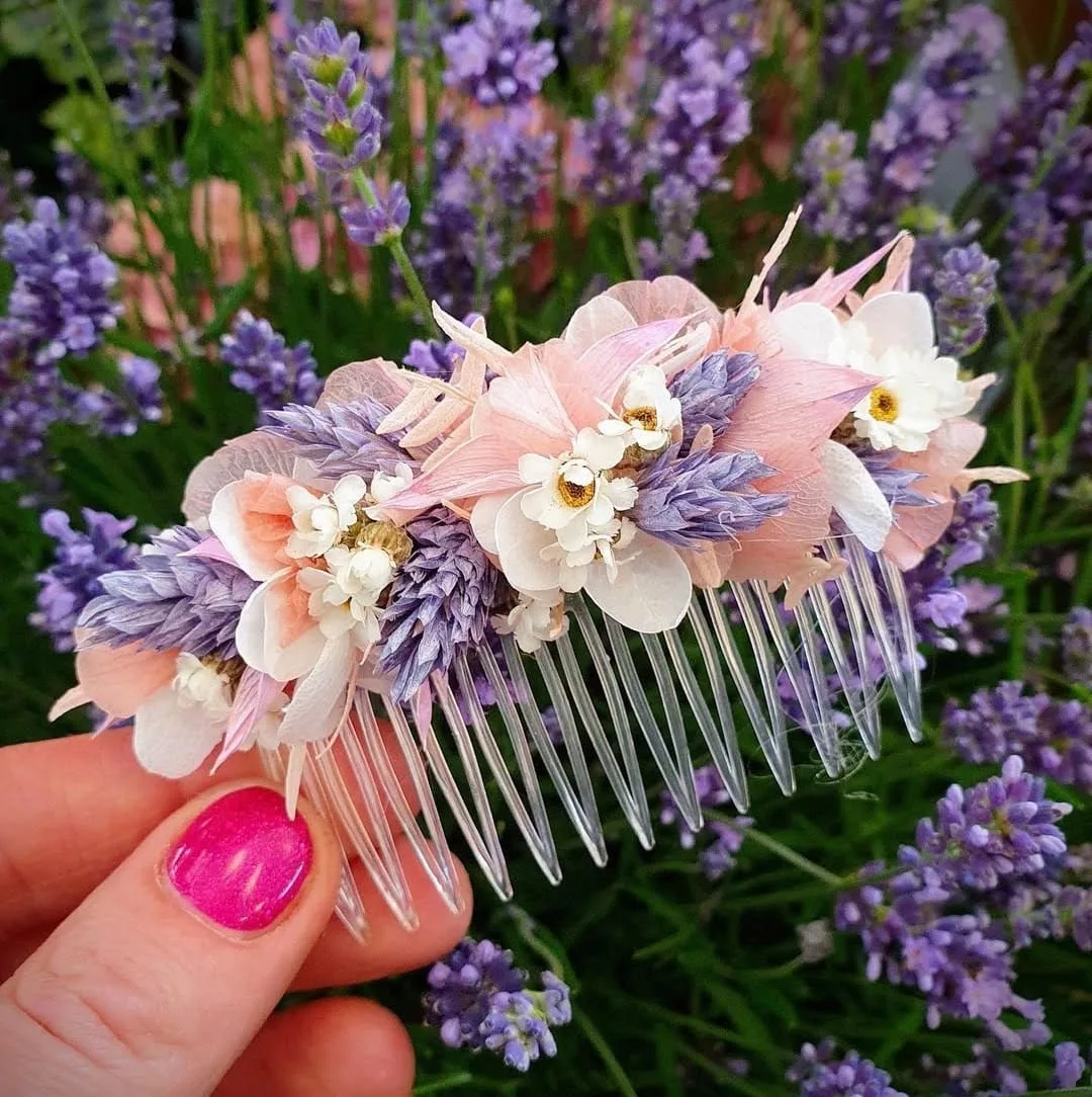 Haarkamm aus getrockneten Blüten in Rosa, Weiß und Lila über Lavendel