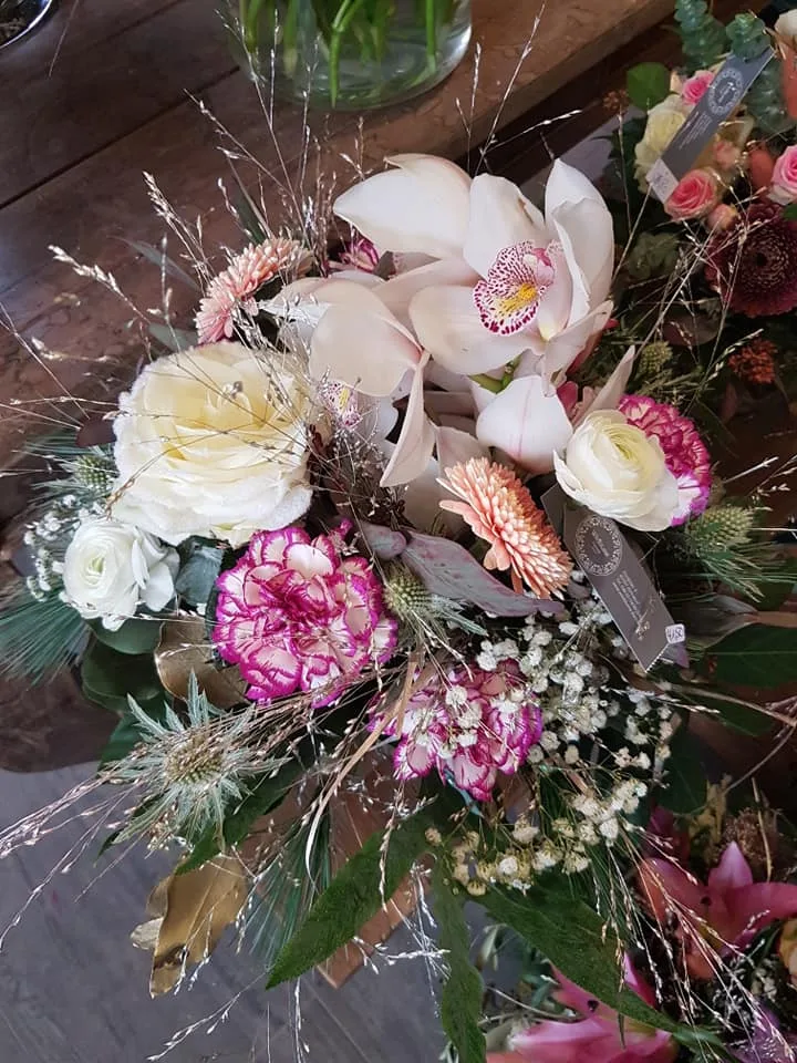 Strauß aus Orchideen, weißen Rosen und Nelken mit Gräsern und Schleierkraut