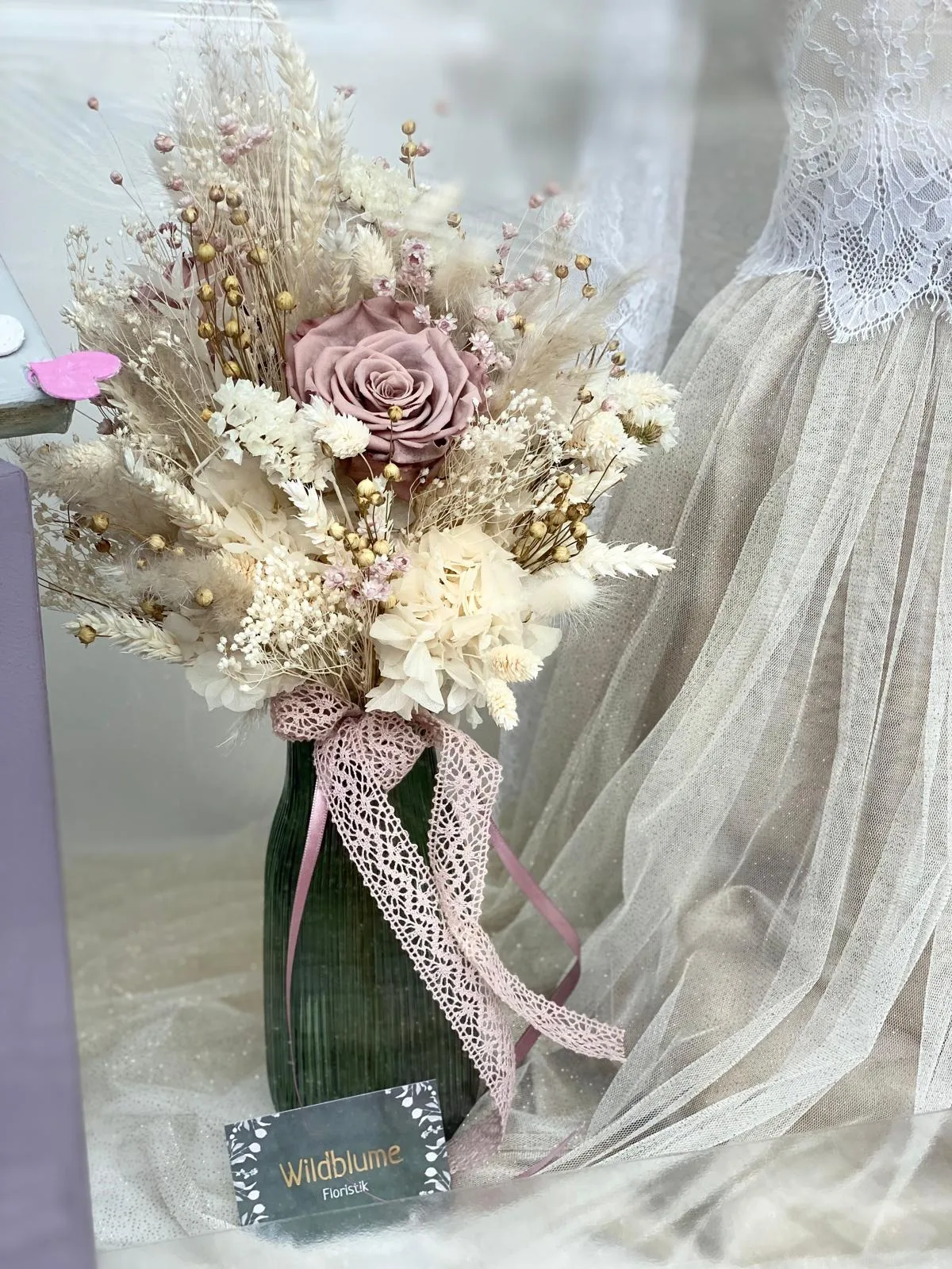 Strauß aus Trockenblumen und Gräsern mit einer altrosa Rose in einer Vase