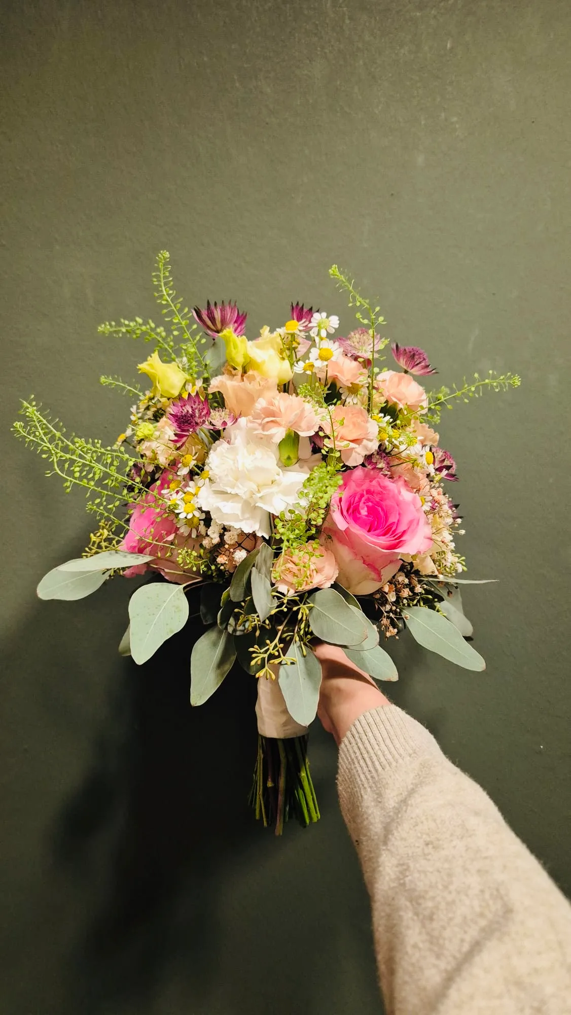 Kleiner Strauß mit Rosen und Nelken in Rosa und Creme, in der Hand gehalten