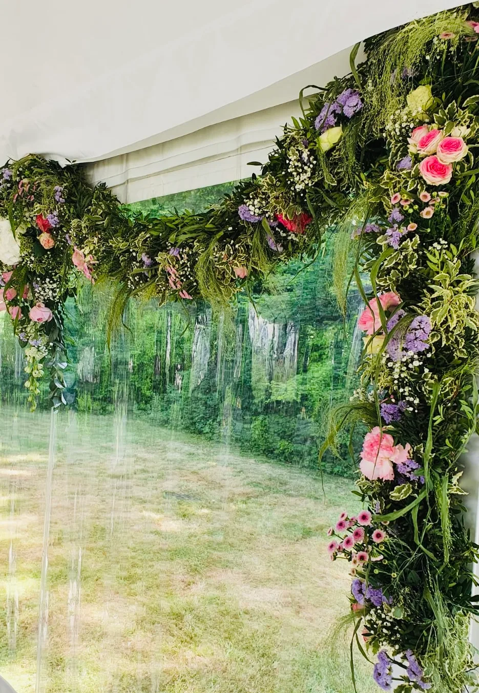 Girlande aus Grün und rosa Blüten am Rahmen eines Festzelts