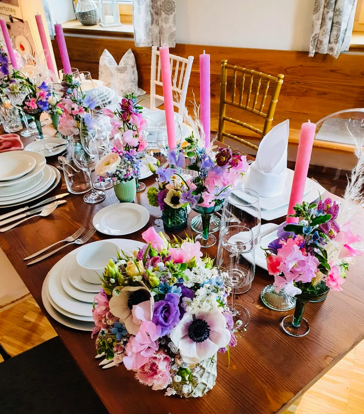 Festlich gedeckter Tisch mit rosa Kerzen und kleinen Vasen mit Anemonen und Wicken