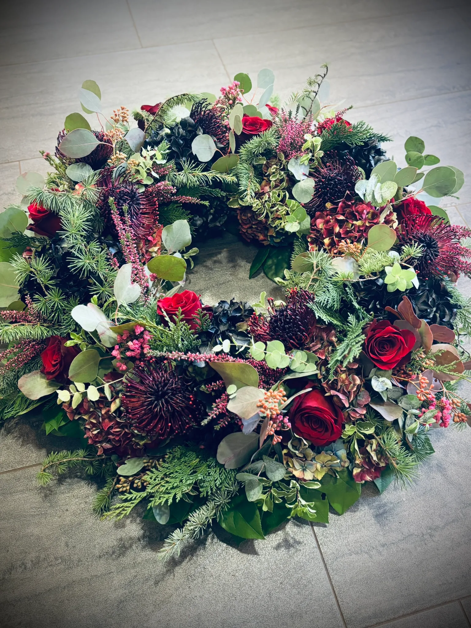 Trauerkranz aus Tannengrün mit roten Rosen und Heide