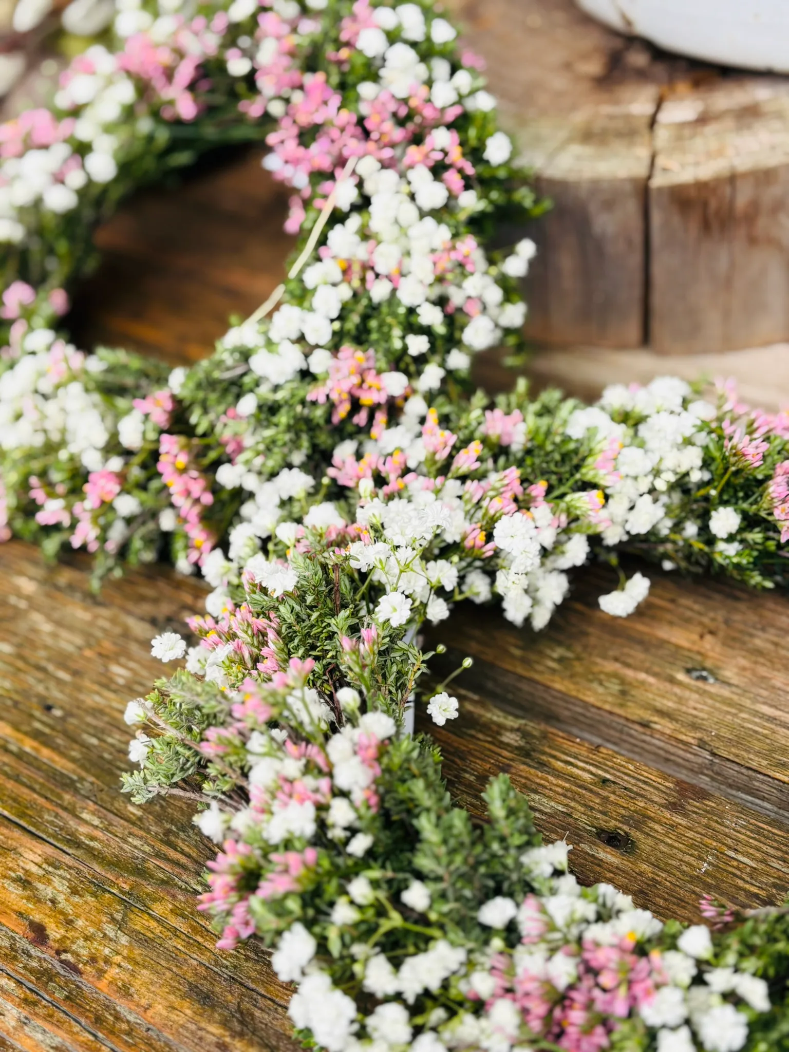Zwei frische Kopfkränze mit Schleierkraut und Wachsblumen in Weiß und Rosa auf Holz
